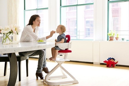 Mother feeding the baby in high chair